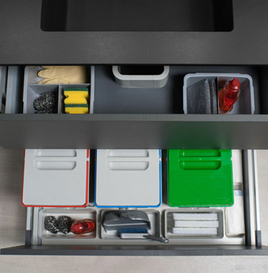 Un cajón diseñado para la eficiencia: contenedores de reciclaje codificados por color y compartimentos organizados para guantes, esponjas y productos de limpieza, todo en un solo lugar, oculto y accesible.