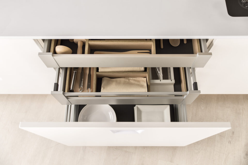Cajones organizados con precisión en una cocina de líneas limpias. El sistema interior modular maximiza el espacio, manteniendo utensilios, textiles y vajilla siempre accesibles y en perfecto orden. Diseño funcional y elegante.