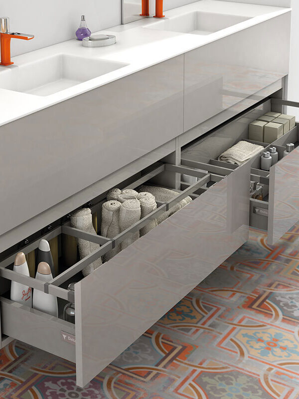 Organización y diseño se fusionan en este mueble de baño: cajones amplios con divisores funcionales que albergan toallas, productos de cuidado personal y accesorios, todo dispuesto con orden y estilo sobre un suelo de patrones vibrantes.